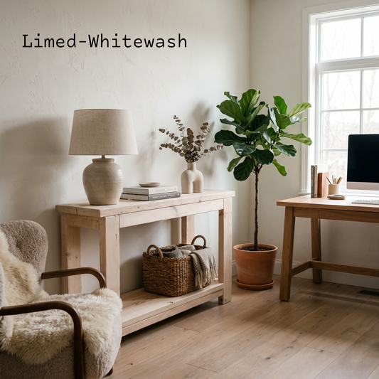 A styled interior scene with a pale wood console table, a table lamp, books, a small vase, a potted fiddle-leaf fig plant, and part of a desk by a window. The text 'Limed-Whitewash' appears in the upper left, suggesting a color or finish option rather than a visible product brand.